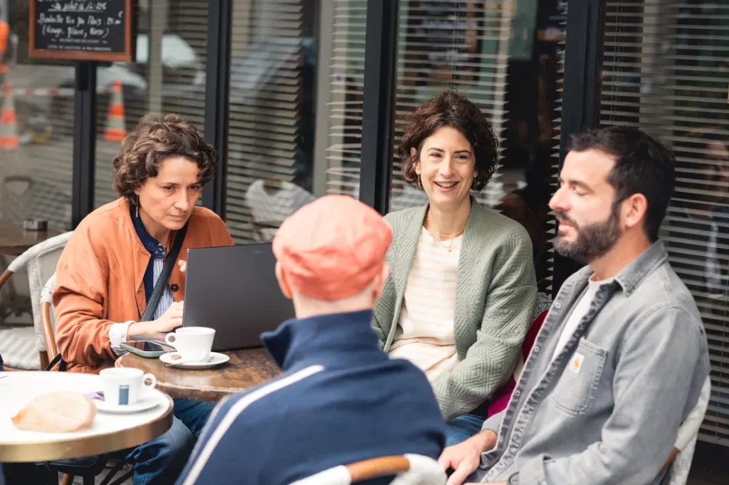 Quatre personnes échangent à la terrasse d’un café